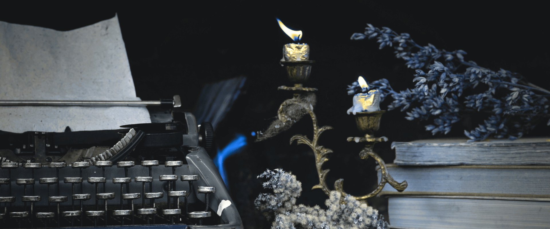 maszyna do pisania, książki i palące się świece