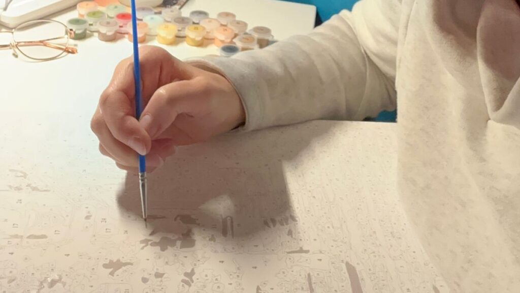 malowanie po numerach przez osobę z pędzlem w dłoni