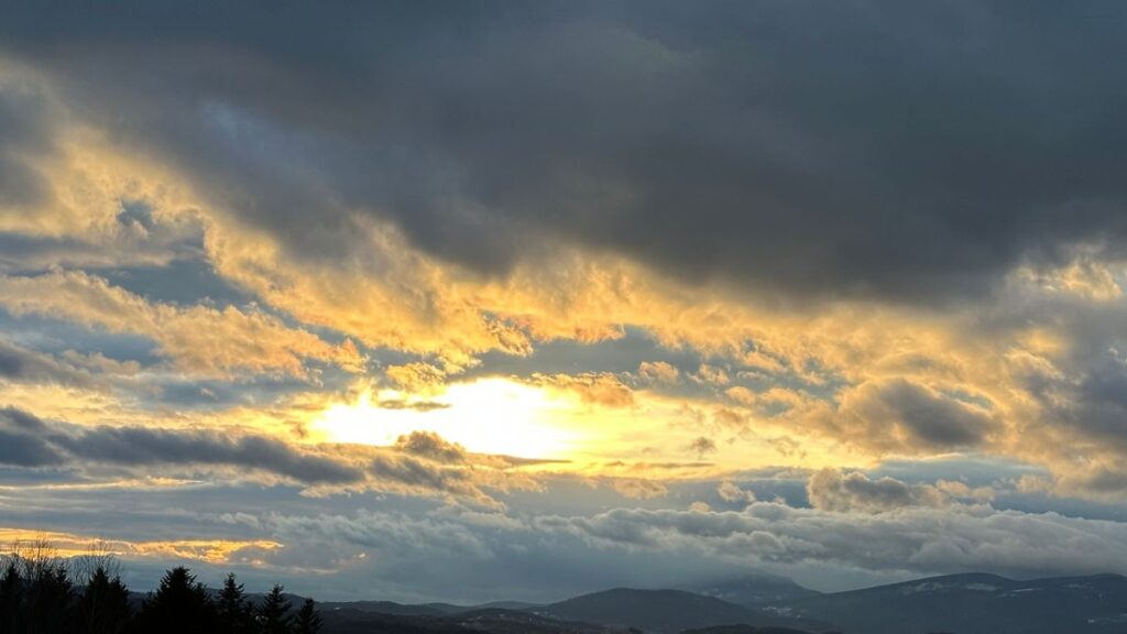 Dramatyczne, ciemne chmury nad górami, przez które przebija się jasne, złote światło słońca. Metafora walki z mrokiem w artykule o tym, że depresja to choroba