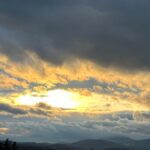 Dramatyczne, ciemne chmury nad górami, przez które przebija się jasne, złote światło słońca. Metafora walki z mrokiem w artykule o tym, że depresja to choroba