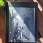 Czytnik ebooków na drewnianym stole z okładką książki Leny Klimki „Gdzie Światło spotyka Mrok” – dystrybucja książki w self-publishingu.